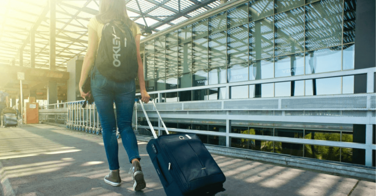 Κοπέλα με βαλίτσα προχωράει προς ένα αεροδρόμιο